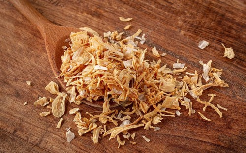 Smoked onion flakes, on a wooden spoon, wooden table, close-up