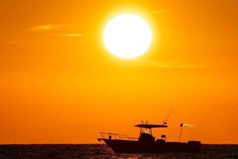 The sun rises behind a boat on the Costa Rei, a coastal section of the Italian Mediterranean island