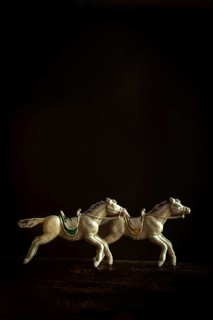 Two intricately designed horse figurines are depicted galloping in sync, creating a sense of