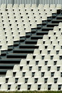 Empty white seats neatly arranged in rows await spectators at a stadium. The absence of an audience