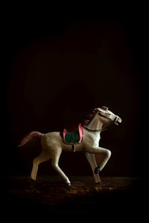 A vintage toy horse trots gracefully across a soft, warm background, highlighting its intricate