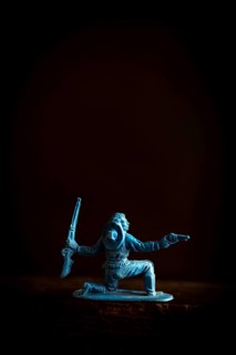 A cowboy figure is captured in a low stance, dynamically poised with two weapons