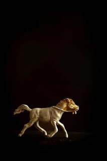 A finely crafted brown wooden horse figure is captured in motion, depicting a galloping stance as