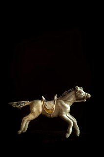 A detailed toy horse is captured in motion, showcasing its intricate design and craftsmanship. The