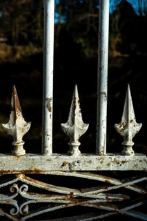 A close view of a vintage iron gate featuring decorative spikes, showcasing rust and wear over time