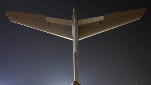 Close-up view of an airplane tail and wings against a clear twilight sky, captured from behind