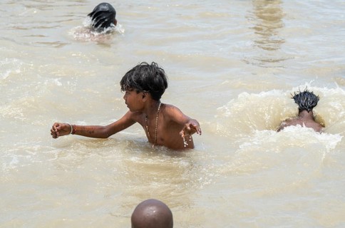 Children bathe in the Brahmaputra River to seek relief from the intense summer heat in Guwahati,