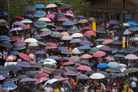 People attend holding umbrellas at an event organised to mark the Behdienkhlam festival in Jowai,