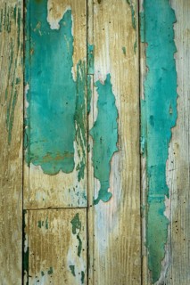 Textures of aged wooden planks show peeling paint in shades of blue and beige, reflecting years of