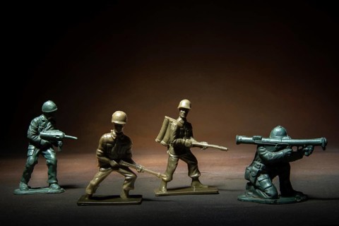 Four miniature soldier figures positioned in a tense standoff, showcasing various combat stances
