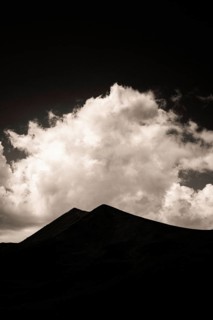 Majestic mountains form a dark outline against a backdrop of swirling clouds illuminated by