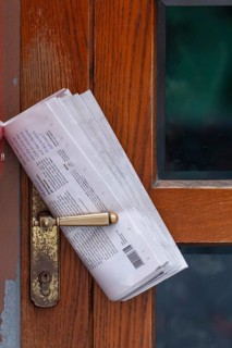Fresh newspaper waiting at the door in the early morning. Newspaper on the door handle