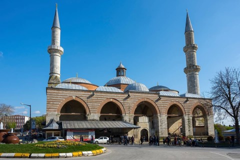 Historic mosque with two minarets on a busy street. The sky is sunny with clear blue. Old Mosque,