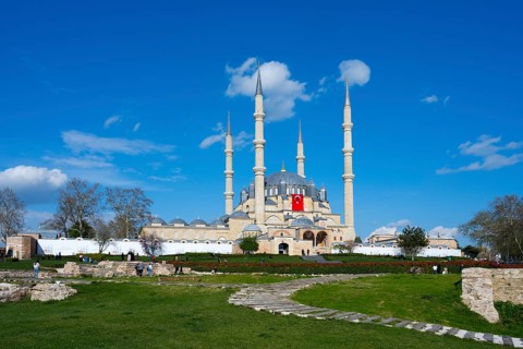 Mosque with dominant minarets and a spacious garden in front of it. Clear day with blue sky.
