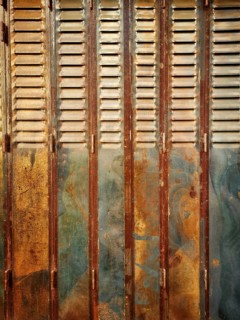 Rustic wooden shutters exhibit a blend of rusty and faded paint, showcasing years of weathering in