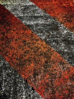 Bold red and black lines create an eye-catching pattern on a rough surface, illuminated by warm