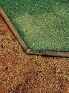 This detailed view captures the unique transition of a playground surface from vibrant green rubber