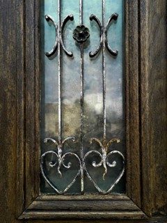 Craftsmanship shines through this wooden door, featuring beautiful metal designs and colorful glass