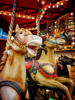 Colorful vintage carousel horses stand at an amusement park, illuminated by soft lights, inviting