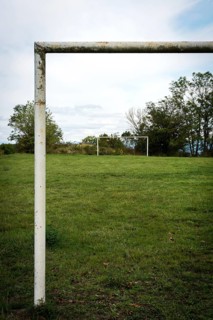 Football goalpost in a grassy field under a cloudy sky near a rural area. Auvergne. France