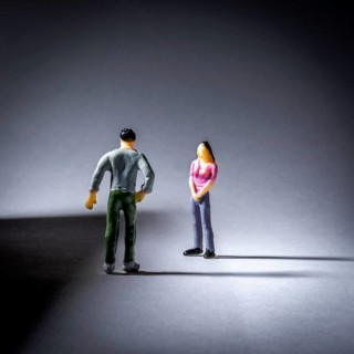 Two small figurines engage in a conversation, with a focus on their body language. The lighting