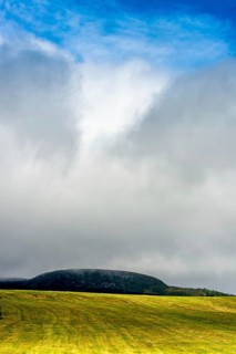 A bright yellow field stretches across the landscape, illuminated by sunlight that peeks through