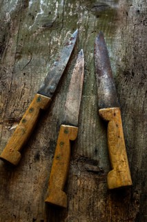 Vintage kitchen knives arranged on rustic wooden surface showcasing unique textures and worn