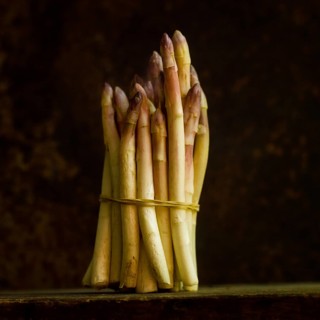 This close up showcases a bundle of fresh asparagus, tightly tied together with a natural twine.