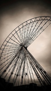 A maintenance worker is seen climbing the structure of a ferris wheel that features vibrant lights.