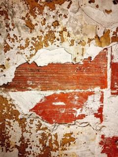 The surface features a combination of peeling paint and exposed brick, highlighting the age and