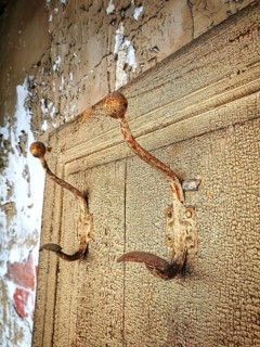 Rusty hooks attached to a weathered wall in a dilapidated building showcasing decay and abandonment