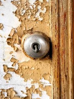 Close view of a keyhole on a weathered, peeling door demonstrates intricate details and textures.