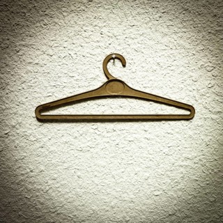 A clothes hanger is suspended from a textured wall, showcasing a minimalist design. The simple