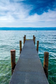 A sturdy jetty extends into the serene waters of Lake Geneva, surrounded by mesmerizing blue hues