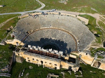 A theatre in an ancient city, surrounded by green hills and impressive architecture, amphitheatre,