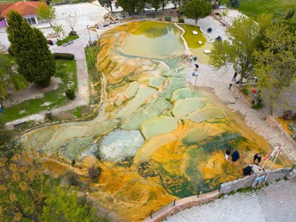Natural terraces of mineral deposits with people in a green environment, aerial view, Karahayit