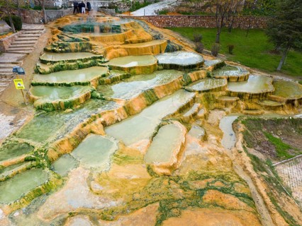 A geothermal landscape with mineral terraces and water accumulations, aerial view, Karahayit
