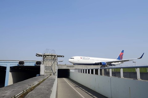 Aeroplane taxiing over a bridge over a road and cycle path, Amsterdam-Schiphol Airport, North