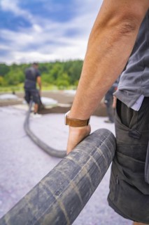 Close-up of a worker holding a thick hose during construction work, roof greening, house
