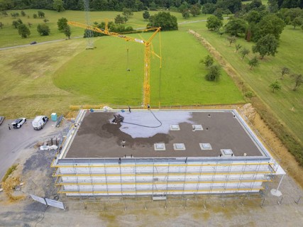 Drone shot of a construction site with crane and partially constructed building on a large green