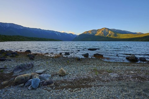 Stony beach on a lake with mountains at sunrise, summer, Lake Rotoiti, Saint Arnaud, Tasman Region,