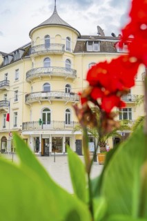Yellow hotel with round balconies, emphasised by a red flower in the foreground, Baden Baden,