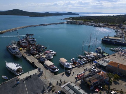 Sunny harbour with boats and yachts, surrounded by azure blue water and landscape, aerial view,