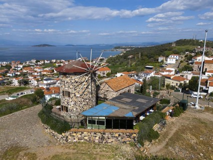 Coastal panorama with striking windmill, surrounded by houses and hills, aerial view, Alibey,