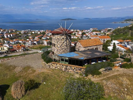 Historic windmill with sea view, surrounded by houses and green landscape, aerial view, Alibey,