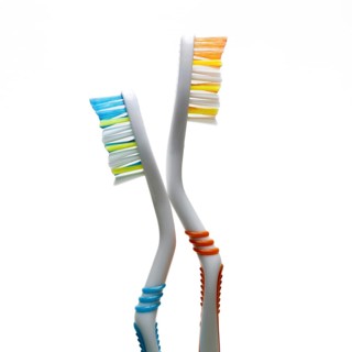 Two vibrantly colored toothbrushes stand at an angle against a plain background. They highlight the