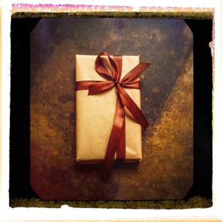 A close-up of a gift parcel elegantly wrapped in brown paper and tied with a satin ribbon, resting