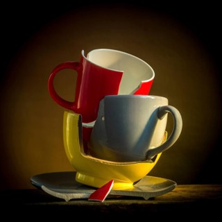 A collection of broken tableware is displayed, featuring a red mug and plate alongside other