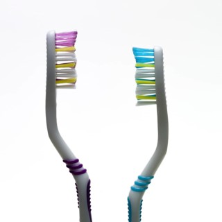 A pair of toothbrushes with bright bristles in pink and blue showcase effective hygiene tools.