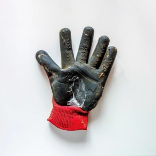 A gardening glove with a black rubber palm and a red knitted cuff is lying flat on a white surface.